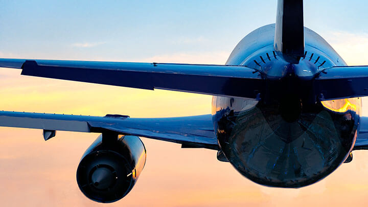 Back view of a large commercial plane taking off at sunset