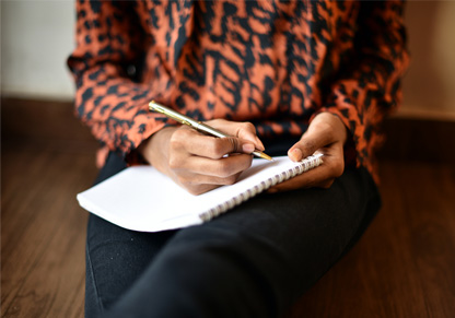 Close up of a hand making notes on a pad. 