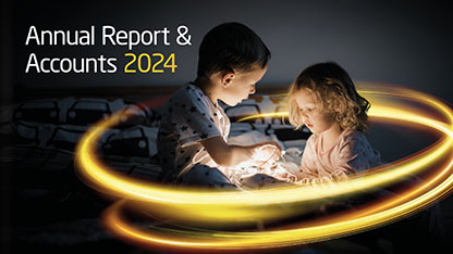 2025 Annual Report cover showing two young children in a dark room holding string lights with a glowing yellow light around them