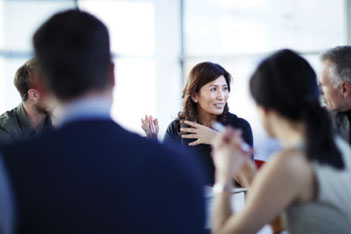 Asian woman speaking to colleagues at a table