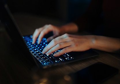 Hands typing on a laptop keyboard. 