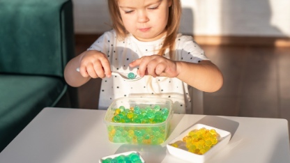 Little girl playing with sensory water beads, hydrogel balls.
