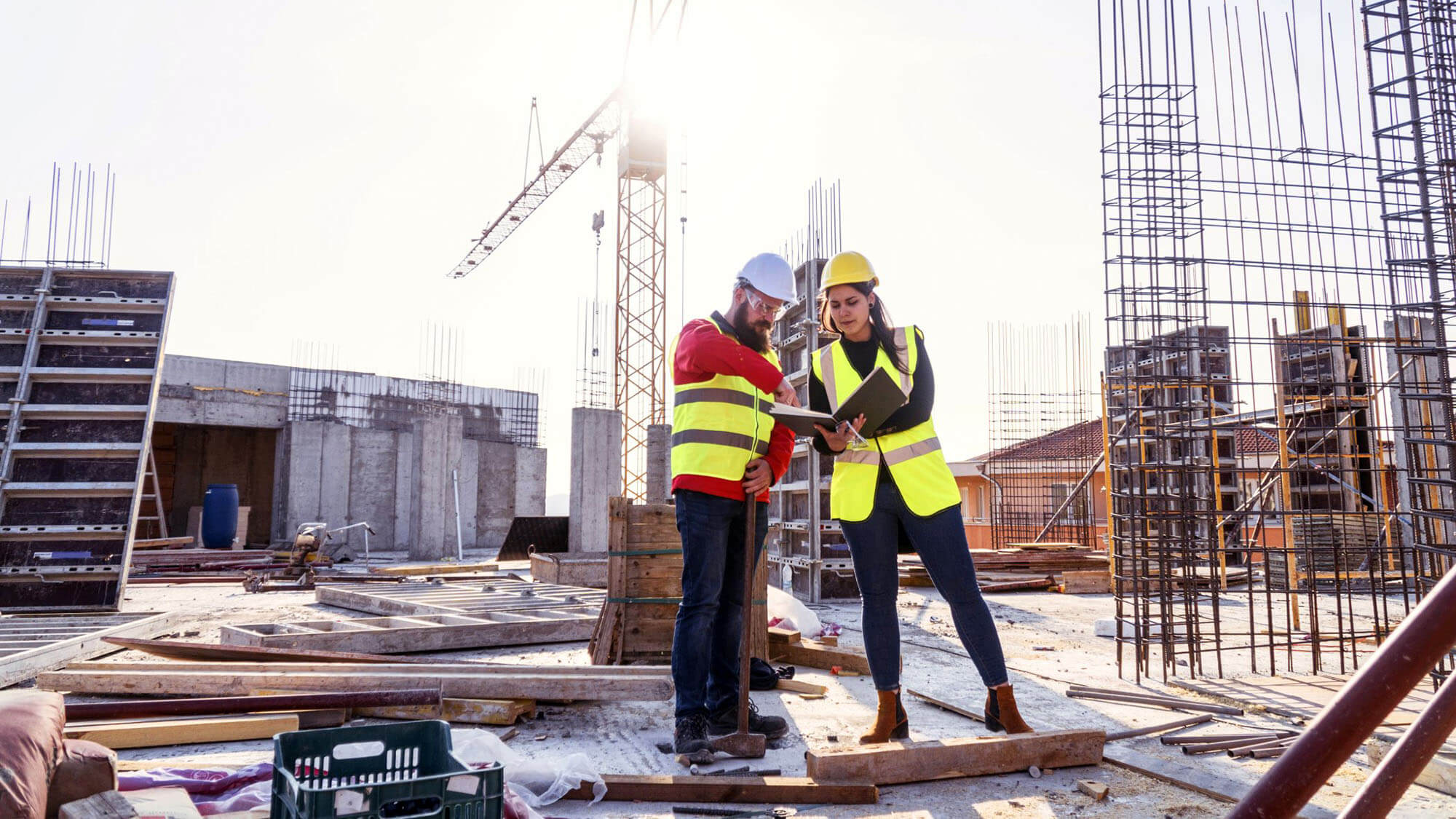 A Teamwork of an Architect - Project Manager and a Construction worker at site of a reinforced concrete building, checking the Progress of the Building Activity.